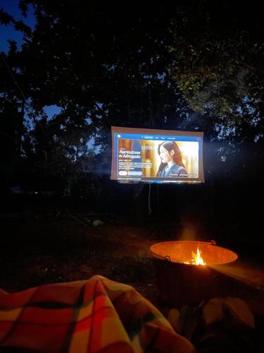 a tv screen in the dark with a tent and a fire at Alojamento 4 in Monção