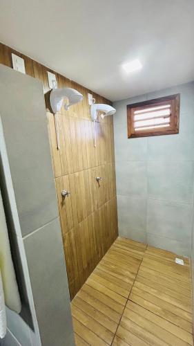 a bathroom with a shower with a wooden door at Mar e Terra Bangalôs in Areia Branca