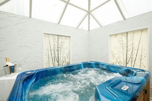 Una bañera azul en una habitación blanca con ventanas en Avenue Motel Palmerston North en Palmerston North
