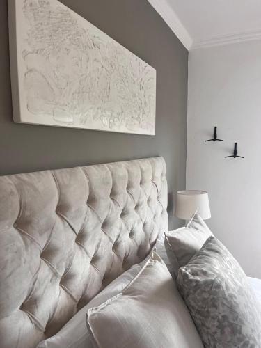 a bedroom with a white tufted bed with a painting at Bo-den-See Guesthouse in Groot Brak Rivier