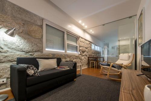 a living room with a black couch and a chair at An apartment with a view - Nó's place in Vila Nova de Gaia