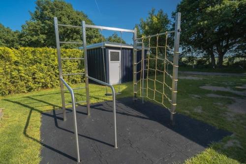 a batting cage in a park with a shed at Ferienhaus mit Pool und Sauna am Duemmer See in Dümmer