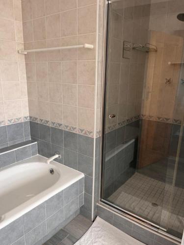 a bathroom with a tub and a shower with a glass door at Bo-den-See Guesthouse in Groot Brak Rivier