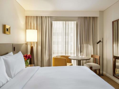 a hotel room with a white bed and a table at Sofitel Sydney Wentworth in Sydney