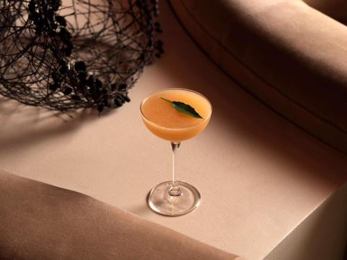 a drink in a glass with a green leaf in it at Sofitel Sydney Wentworth in Sydney