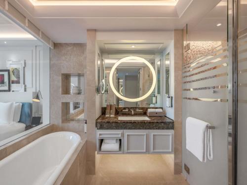 a bathroom with a tub and a sink and a mirror at Sofitel Bangkok Sukhumvit in Bangkok