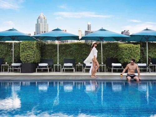 a woman and a man sitting next to a swimming pool at Sofitel Bangkok Sukhumvit in Bangkok