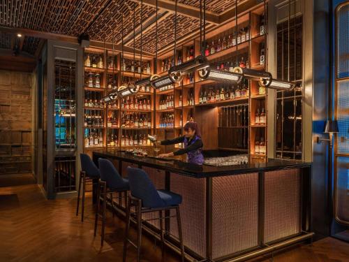 a woman standing at a bar in a room with alcohol bottles at Sofitel Bangkok Sukhumvit in Bangkok