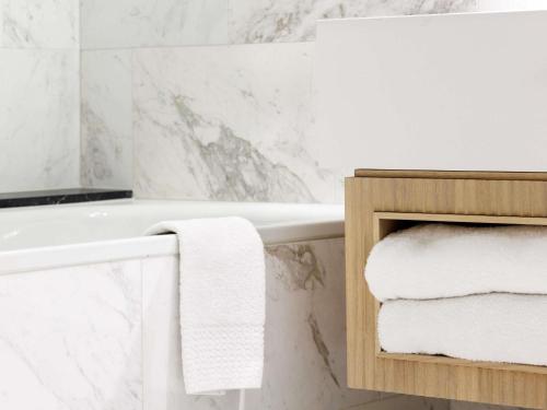 a white bathroom with a bath tub and towels at Sofitel Brussels Europe in Brussels