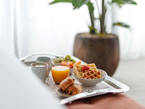 a breakfast tray with breakfast foods and orange juice at Sofitel Brussels Europe in Brussels