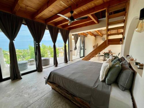 a bedroom with a large bed and large windows at Maison de Reve - Boutique Guest House in Brisas de Zicatela