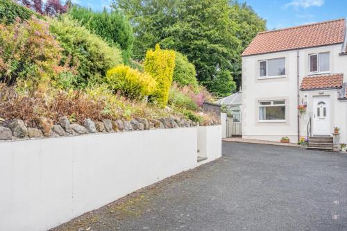 a house with a white fence and a driveway at Lionels Den in Wooler