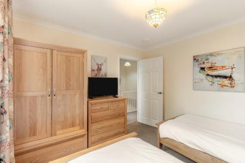 a bedroom with a bed and a tv on a dresser at Lionels Den in Wooler