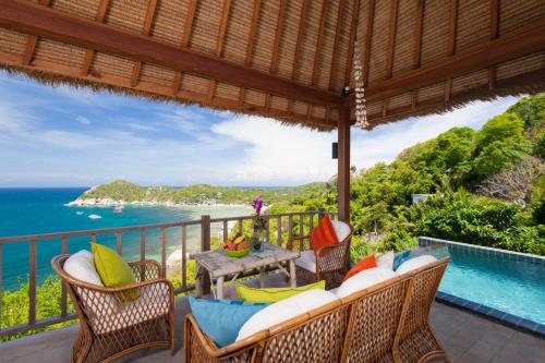 an outdoor patio with a table and chairs and the ocean at The Fisherman's Villas in Koh Tao