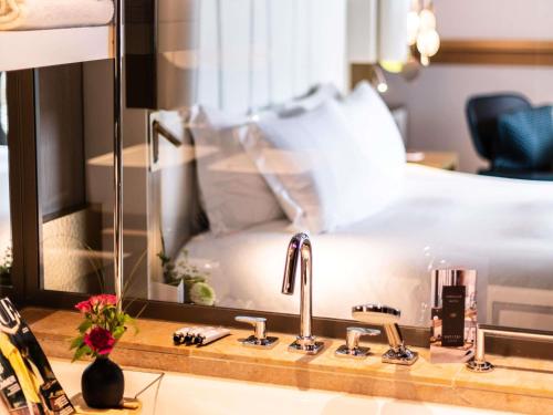 a bathroom sink with a mirror and a bed at Sofitel Munich Bayerpost in Munich