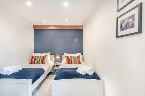 two beds in a room with blue walls at Swallows Barn in Little Snoring