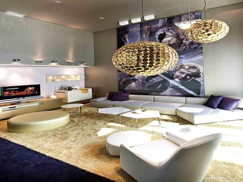 a living room with a couch and a tv at Sofitel Munich Bayerpost in Munich