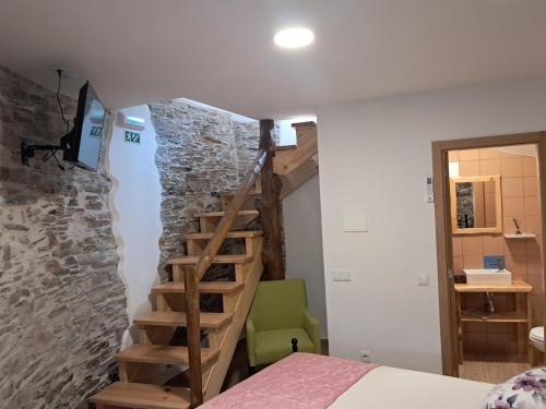 a bedroom with a staircase in a stone wall at AL Rossadas Giesta in Arganil