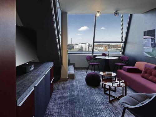 a living room with a couch and a large window at Sofitel Munich Bayerpost in Munich