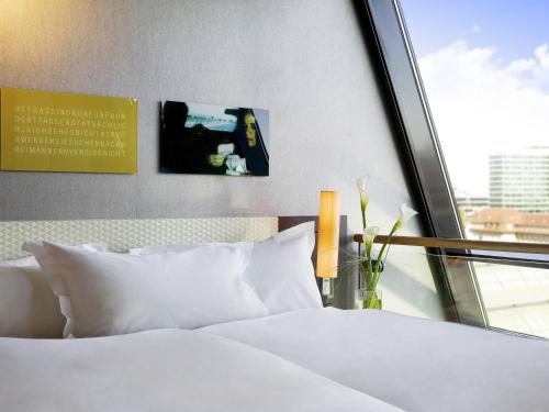 a bedroom with a bed with white sheets and a window at Sofitel Munich Bayerpost in Munich