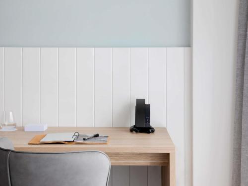 a desk with a chair and a speaker on it at Manly Pacific Sydney MGallery Collection in Sydney