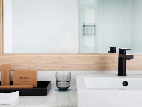 a bathroom with a sink and a glass on a counter at Manly Pacific Sydney MGallery Collection in Sydney