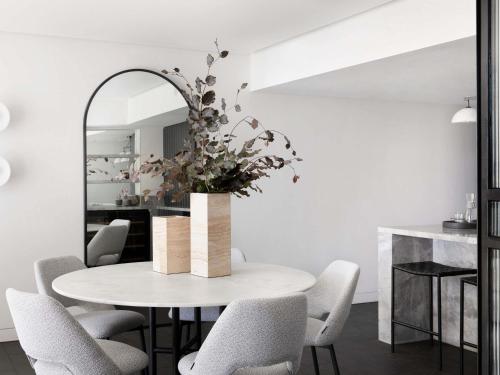 a dining room with a table with chairs and a mirror at Manly Pacific Sydney MGallery Collection in Sydney