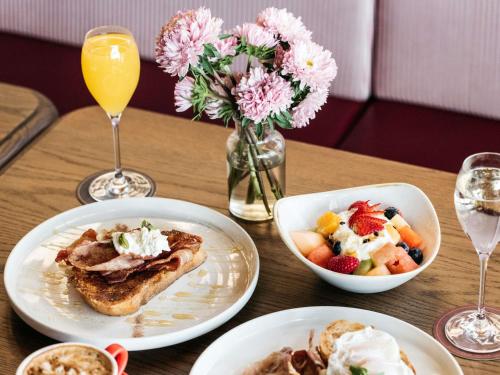 a table with two plates of food and a bowl of fruit at Manly Pacific Sydney MGallery Collection in Sydney