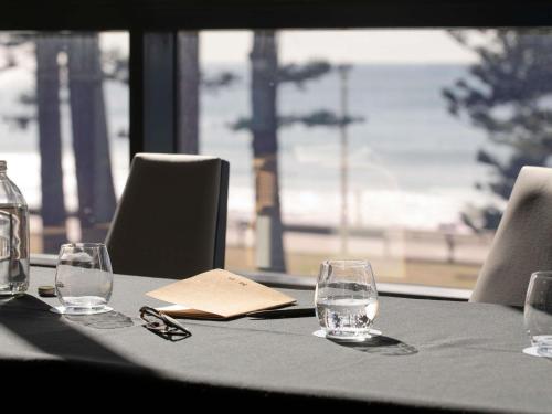 a table with two wine glasses and a napkin at Manly Pacific Sydney MGallery Collection in Sydney