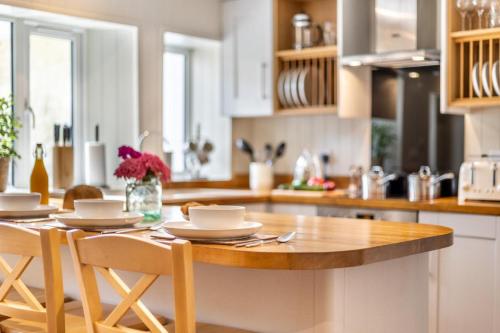 a kitchen with a wooden table with chairs and a counter at The Anchorage - Snettisham in Snettisham