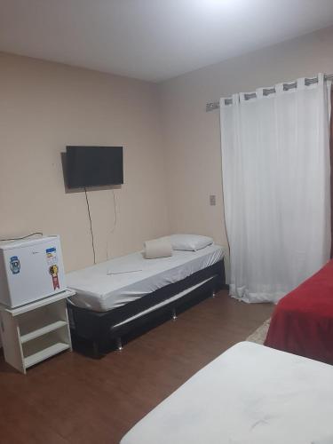 a room with two beds and a tv in it at Pousada Village Hostel in Petrópolis