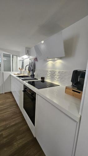 une cuisine blanche avec une cuisinière et un évier dans l'établissement le stockholm, à Sablons