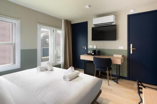 a room with two beds and a desk and a tv at Hotel Zeedijk City Centre in Amsterdam
