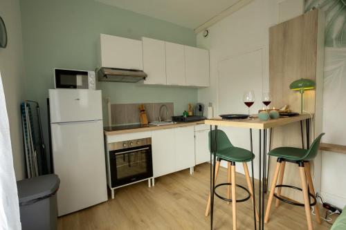 a kitchen with white cabinets and green bar stools at Jungle Studio - Déco tropicale et confort moderne in Montoir-de-Bretagne