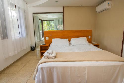 a bedroom with a large bed with white sheets at Pousada Valle dos Pássaros in Penedo