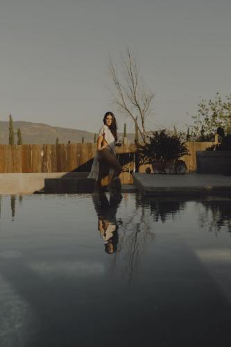 a woman is sitting on a skateboard next to a pool of water at Casa Michaus Valle de Guadalupe in Valle de Guadalupe