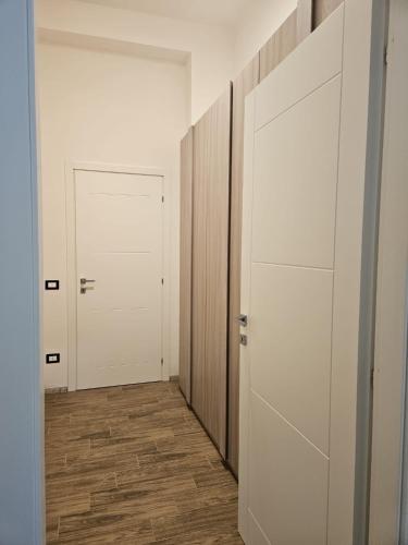 a hallway with two white doors and a wooden floor at Elysium Affittacamere in Mazara del Vallo