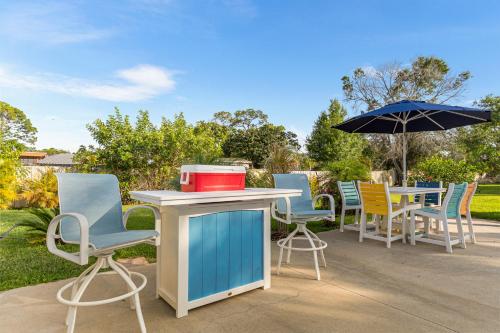 a group of chairs and tables with an umbrella at Paradise in Time in Port Saint Lucie