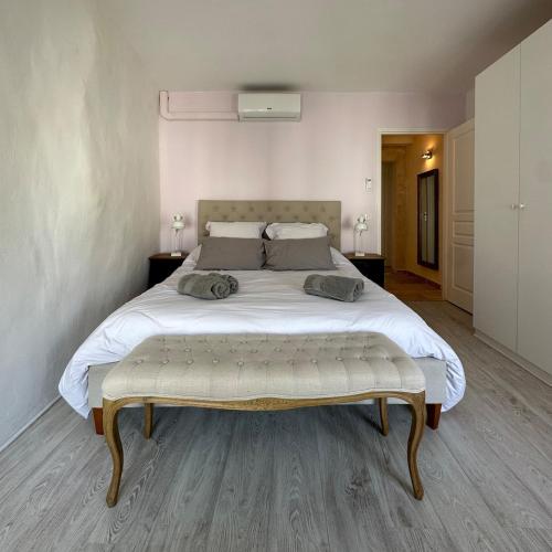 a bedroom with a large white bed with a bench at the end at Spacieux T3 en duplex rénové avec terrasse in Saint-Rémy-de-Provence