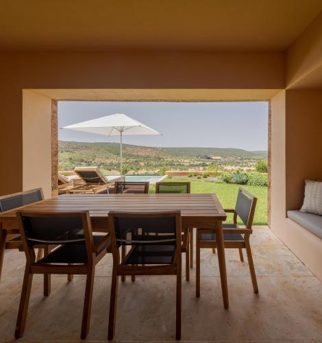 a dining room with a table and chairs and an umbrella at Viceroy at Ombria Algarve in Loulé