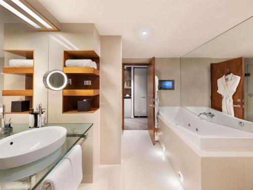 a bathroom with a large tub and a sink at Sofitel Queenstown Hotel & Spa in Queenstown
