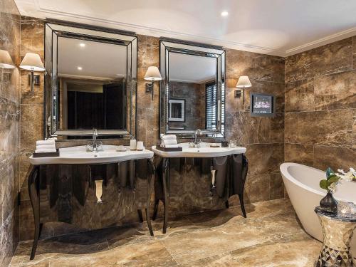 a bathroom with two sinks and a bath tub and a tubermottermott at Sofitel Queenstown Hotel & Spa in Queenstown