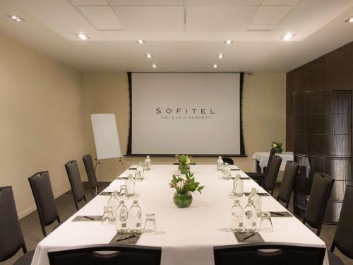 a conference room with a long table with chairs and a screen at Sofitel Queenstown Hotel & Spa in Queenstown