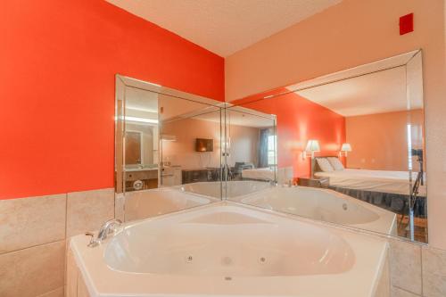 bañera grande en una habitación con pared de color naranja en Capital O Fairway Inn - Baytown La Porte TX, en La Porte