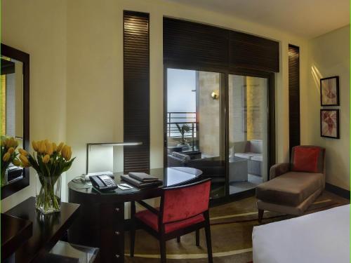 a living room with a desk and a chair and a table with flowers at Sofitel Al Khobar The Corniche in Al Khobar
