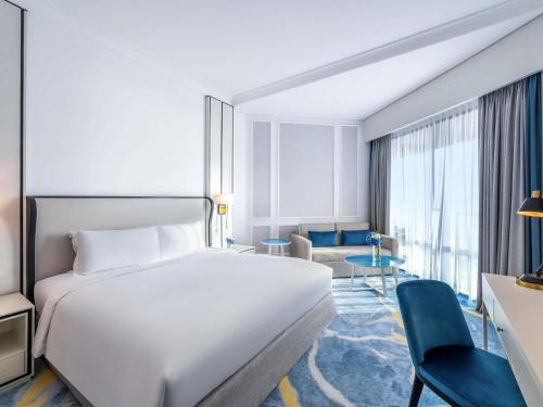 a hotel room with a white bed and a couch at Sofitel Dubai Jumeirah Beach in Dubai