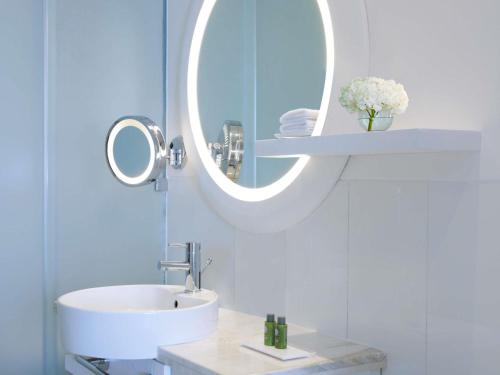 a white bathroom with a sink and a mirror at Sofitel Dubai Jumeirah Beach in Dubai