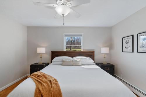 a bedroom with a large white bed with two lamps at High-End Finger Lakes Escape - Expansive Game Room, Cozy Firepit, & Scenic Views in Penn Yan