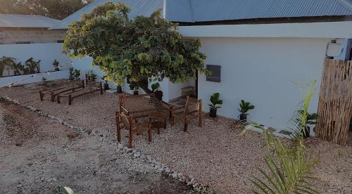 a group of benches and a tree next to a building at Cocohut Zanzibar - Kendwa & Nungwi in Kendwa
