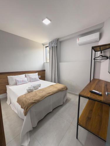 a bedroom with a large bed and a table at FLAT CAMBUCI - Hospedagem e Moradia - Centro de Ipiaú-BA in Ipiaú